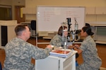 An Air Force student in the Ophthalmic Technician Program at the Medical Education and Training Campus conducts an “eye exam” on a fellow student as an Army instructor observes. Students who graduate from the METC Ophthalmic Technician Program then sit for the Certified Paraoptometric Technician exam average a 98 percent first-time pass rate. (Photo by Dewite Wehrman, Medical Education and Training Campus Public Affairs)