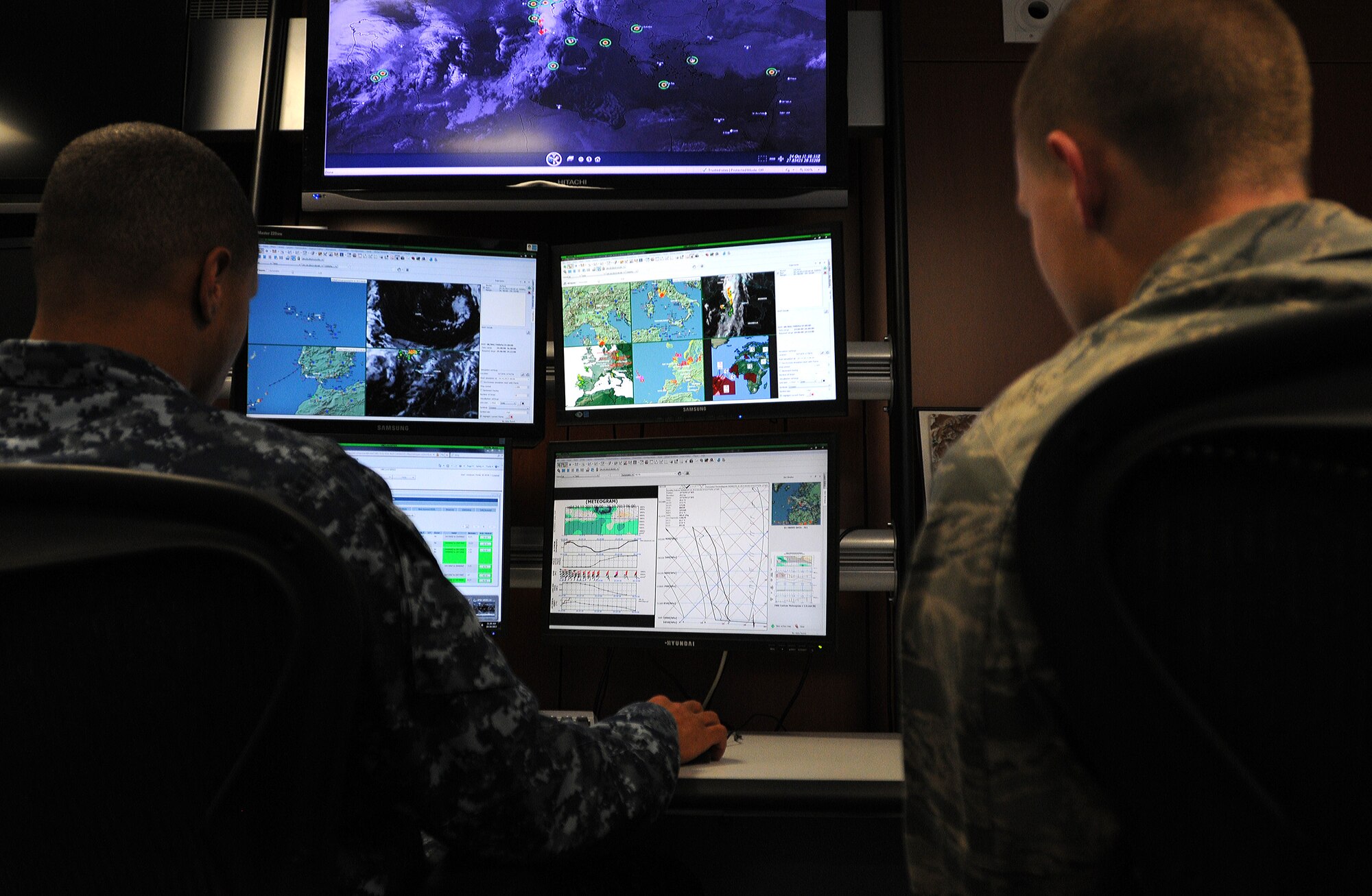 Aerographers Mate 1st Class Rhyan Winbush and 2nd Lt. Brian Popick, 21st Operational Weather Squadron weather forecasters, observe maps of different areas to predict the weather before participating in an evacuation exercise, Oct. 24, 2013, Kapaun Air Station, Germany. The 21st OWS conducts inspections every quarter to prepare operations at an alternate location if the primary location can’t be accessed. (U.S. Air Force photo/Airman 1st Class Holly Mansfield)