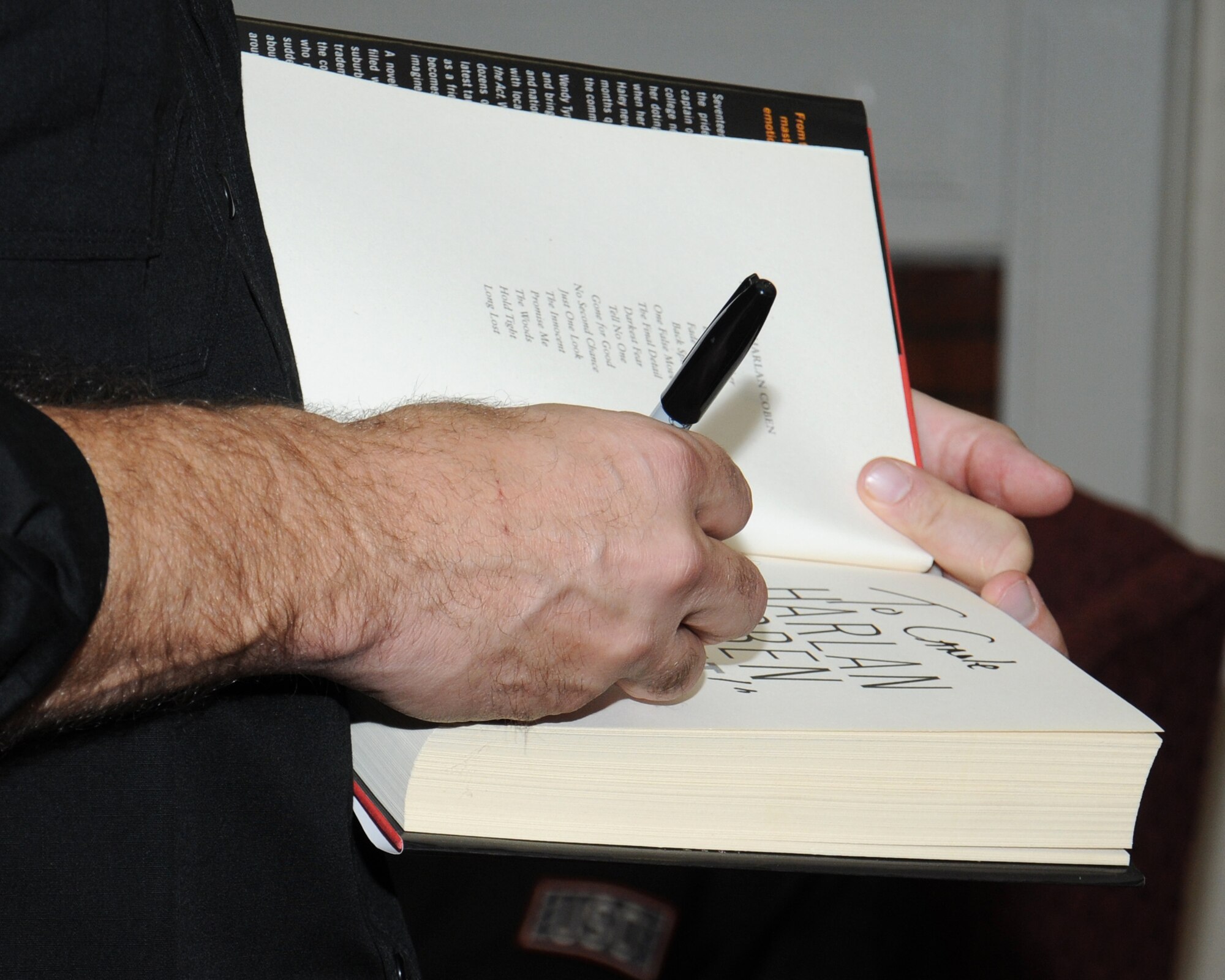 Harlan Coben, author, signs a copy of his book for a fan Oct. 31, 2013, at the library on RAF Mildenhall, England. Authors Kathleen Antrim, Phillip Margolin, Coben, F. Paul Wilson and Heather Graham took part in a book-signing event in the base library as part of the USO tour, Operation Thriller IV. Following the book-signing event, some of the authors returned to the U.S., while others continued on to Brighton, England, for a fantasy writers’ convention.  (U.S. Air Force photo by Gina Randall/Released) 
