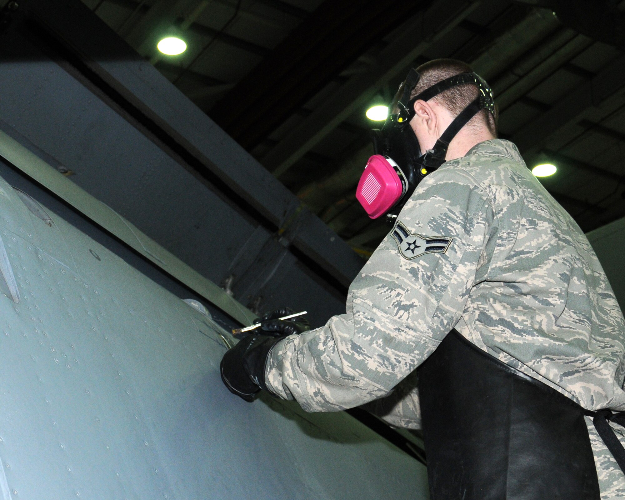 U.S. Air Force Airman 1st Class Cody Leaders, 100th Maintenance Squadron aircraft structural maintenance apprentice from Denver, Colo., chemically removes paint from a KC-135 Stratotanker flap to facilitate inspection of a crack in the skin Oct. 25, 2013, on RAF Mildenhall, England. The 100th MXS aircraft maintenance shop personnel identify, remove and treat corrosion using mechanical and chemical procedures and applying protective coatings. The service members manage structural repair and corrosion control actions on 15 KC-135R Stratotankers, one RC-135, nine C-130s and two CV-22s. (U.S. Air Force photo by Gina Randall/Released)