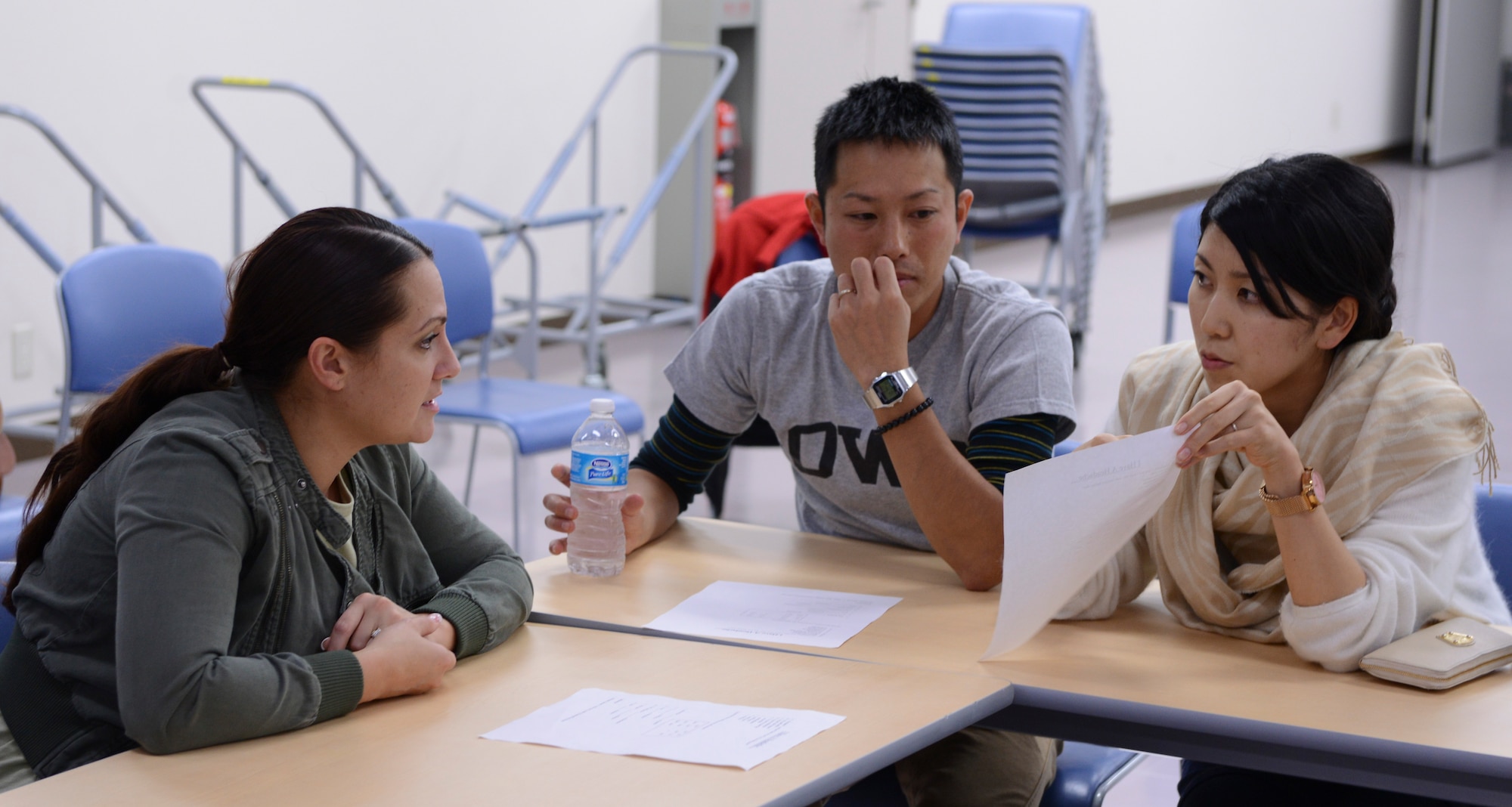 Tech. Sgt. Laury Napoleoni, language class volunteer, helps two Japan Air Self-Defense Force members pronounce English sentences correctly during a conversational English class at Yokota Air Base, Japan, Oct. 30, 2013. The class is held every other week. (U.S. Air Force photo by Senior Airman Michael Washburn/Released)