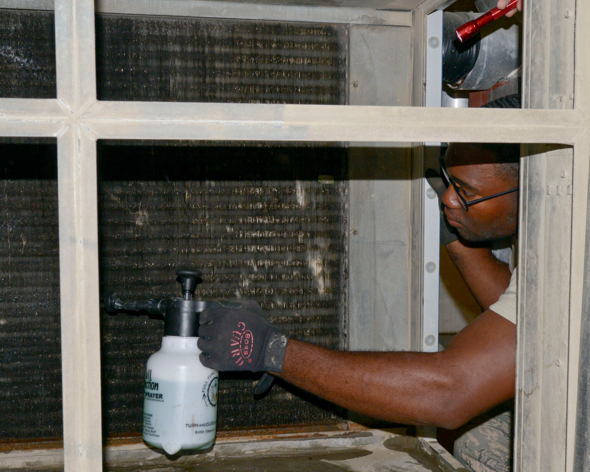 Senior Airman Martini Frazier sprays simple green solution on the coils of a chiller unit at the 379th Air Expeditionary Wing in Southwest Asia, Oct. 22, 2013. The cleaning solution breaks down dirt and grease accumulated between the monthly service and maintenance period.  Frazier is a 379th Civil Engineer Squadron Heating, Ventilation and Air Conditioning technician deployed from Holloman Air Force Base, N.M., and hails from Greeneville, Miss. (U.S. Air Force photo/Tech. Sgt. Joselito Aribuabo)