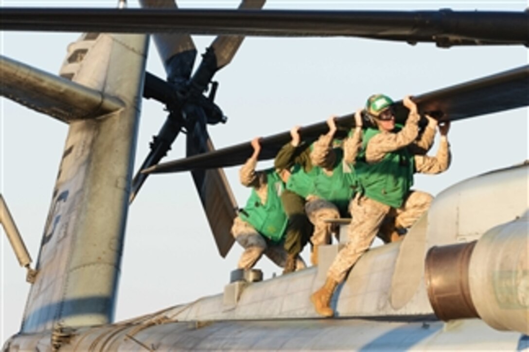 U.S. Marines from the 22nd Marine Expeditionary Unit align the rotor blades of a CH-53E Super Stallion helicopter for stowage following a day of flight operations aboard the amphibious assault ship USS Bataan (LHD 5) as the ship operates in the Atlantic Ocean on Oct. 24, 2013.  The Bataan and the 22nd Marine Expeditionary Unit are underway conducting routine qualifications.  