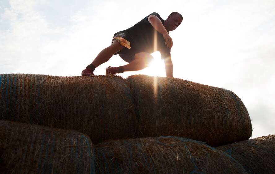 A runner leaps over a hay bale obstacle during the Emerald Coast MudRun for Orphans in Niceville Fla., May 18, 2013.  Active-duty and reserve service members from Duke and Hurlburt Field, Eglin Air Force Base and more came out to get dirty in either the five-mile warrior challenge or the other 5K races throughout the day.  More than 1,000 runners attended the event.  (U.S. Air Force photo/Tech. Sgt. Sam King)