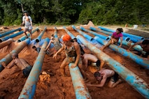 Runners crawl over and under a pipe obstacle during the Emerald Coast MudRun for Orphans in Niceville Fla., May 18, 2013.  Active-duty and reserve service members from Duke and Hurlburt Field, Eglin Air Force Base and more came out to get dirty in either the five-mile warrior challenge or the other 5K races throughout the day.  More than 1,000 runners attended the event.  (U.S. Air Force photo/Tech. Sgt. Sam King)