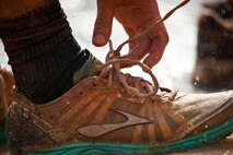 A runner reaches down to tie their shoe while running the Emerald Coast MudRun for Orphans in Niceville Fla., May 18, 2013.  Active-duty and reserve service members from Duke and Hurlburt Field, Eglin Air Force Base and more came out to get dirty in either the five-mile warrior challenge or the other 5K races throughout the day.  More than 1,000 runners attended the event.  (U.S. Air Force photo/Tech. Sgt. Sam King)