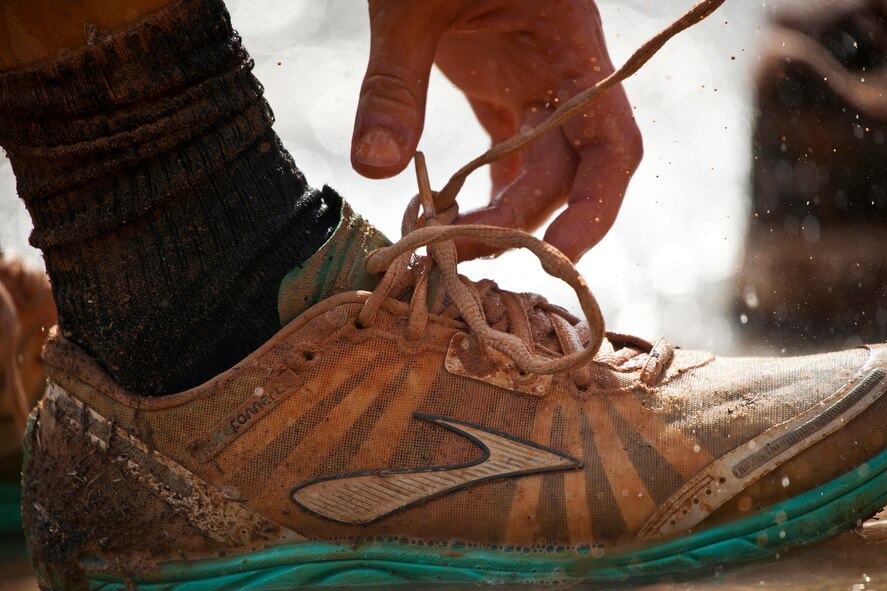 A runner reaches down to tie their shoe while running the Emerald Coast MudRun for Orphans in Niceville Fla., May 18, 2013.  Active-duty and reserve service members from Duke and Hurlburt Field, Eglin Air Force Base and more came out to get dirty in either the five-mile warrior challenge or the other 5K races throughout the day.  More than 1,000 runners attended the event.  (U.S. Air Force photo/Tech. Sgt. Sam King)