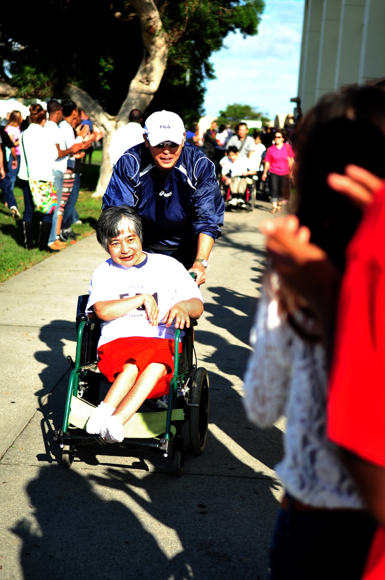 Volunteers cheer 66 years old Ritsuko Higa, as she moves through a crowd during the Kadena Special Olympics on Kadena Air Base, Japan, Nov. 2, 2013. More than 1,300 artists and athletes participated in a variety of events ranging from 200 and 300 meter races, tennis skills and floor hockey to soccer skills and ground golf during the 14th annual KSO. (U.S. Air Force photo by Staff Sgt. Amber E. N. Jacobs)