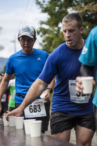 Cpl. Justin Harris, an air traffic controller with Headquarters and Headquarters Squadron, grabs a water cup during the Hagi Iwami Airport Half Marathon Oct. 20, 2013. Mai Tajima, a recreation specialist with SemperFit, Marine Corps Community Services, said she brought 17 service members to the half marathon this year.