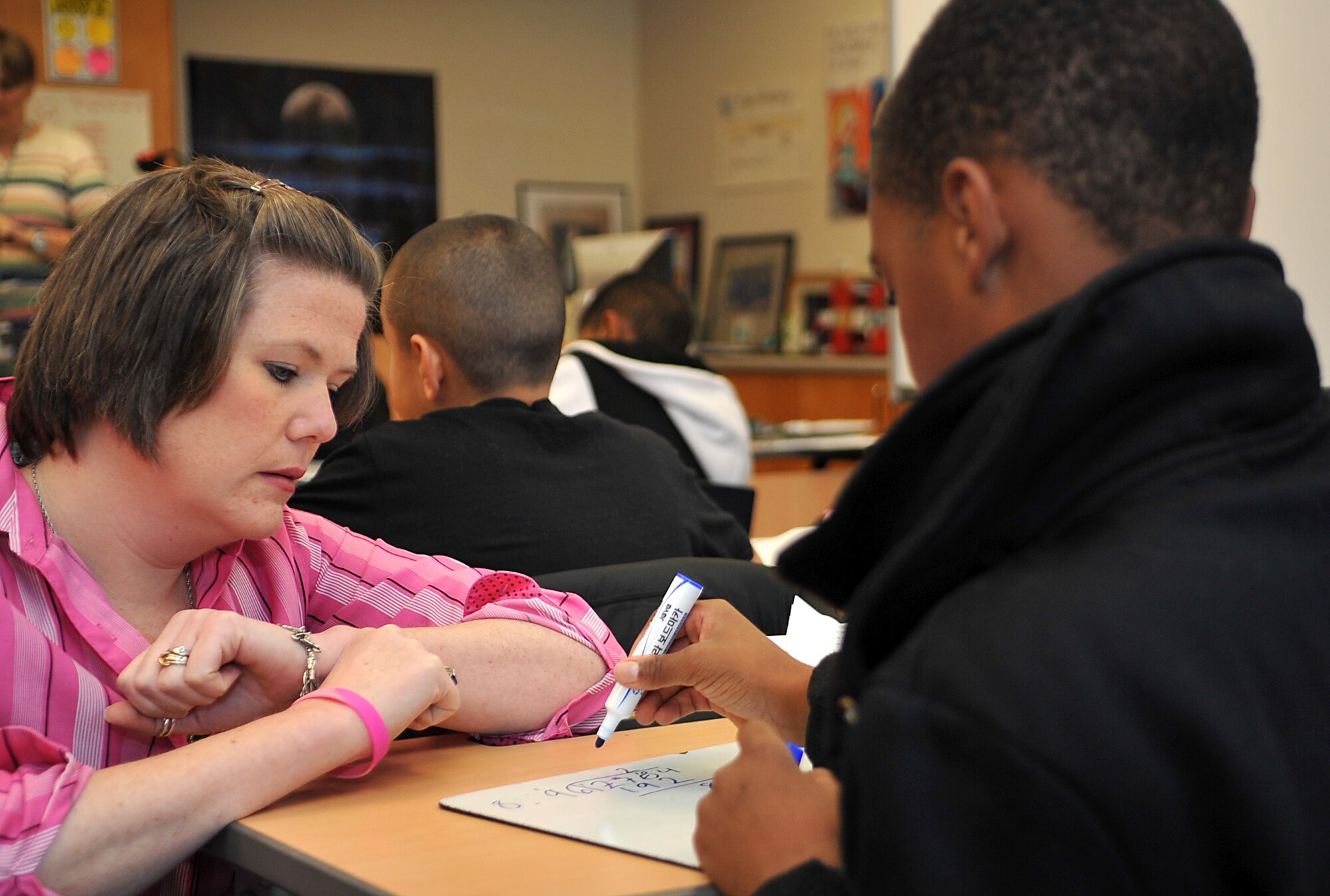 Katie Hampton, Osan Middle School special education teacher and breast cancer survivor, helps a student with his assignment during one of her classes at Osan Air Base, Republic of Korea, Oct. 28, 2013. Hampton was diagnosed with Triple Negative Breast Cancer in February 2012, and after treatment has now been cancer-free for an entire year. (U.S. Air Force photo/Airman 1st Class Ashley J. Thum)