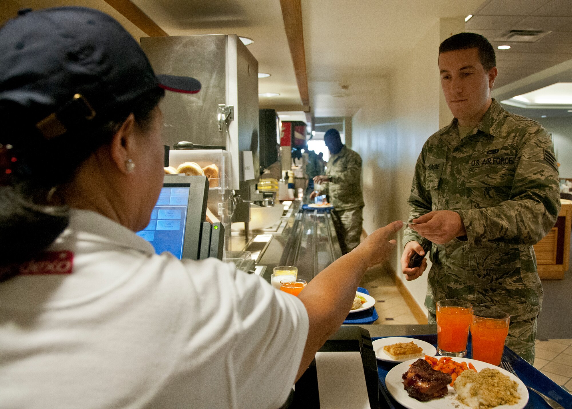 Staff Sgt. Kyle Champagne hands over his ID card for scanning before eating at the Duke Field dining facility.  A new contractor, Sodexo, brought about changes to the way Airmen pay for meals during the unit training assembly and the order in which they are served.  (U.S. Air Force photo/Tech. Sgt. Sam King)