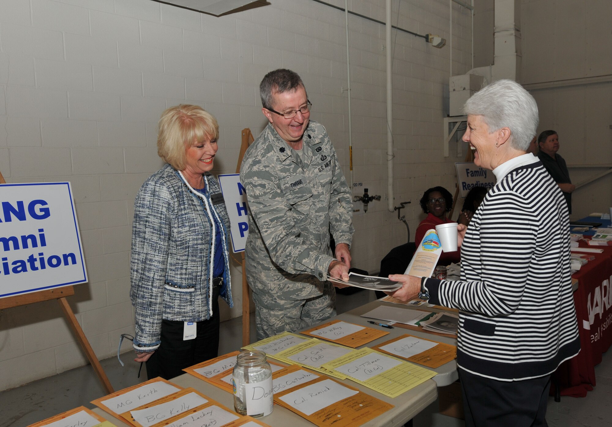U.S. Air Force Lt. Col. David Thrams, Executive Officer for the 145th Maintenance Group, North Carolina Air National Guard, gives Sherry Hamrick, a former member of the 156th Aeromedical Evacuation Squadron, old photos of herself taken when she served in the NCANG.  Hamrick along with more than 150 other retirees attended the 18th Annual Retiree Breakfast held in a hanger at the North Carolina Air National Guard base, Charlotte Douglas Intl. Airport, Friday 25, 2013. (Air National Guard photo by Master Sgt. Patricia F. Moran/Released) 