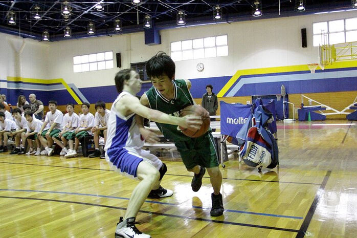 Shinji Hoshide, a Yanai Junior High School student and basketball player, and Michael Coletta, a Matthew C. Perry High School student and team Teddy Bears player, jump for the tip-off in the beginning of the championship game of the basketball tournament held in the IronWorks Gym sports court here Feb. 11.