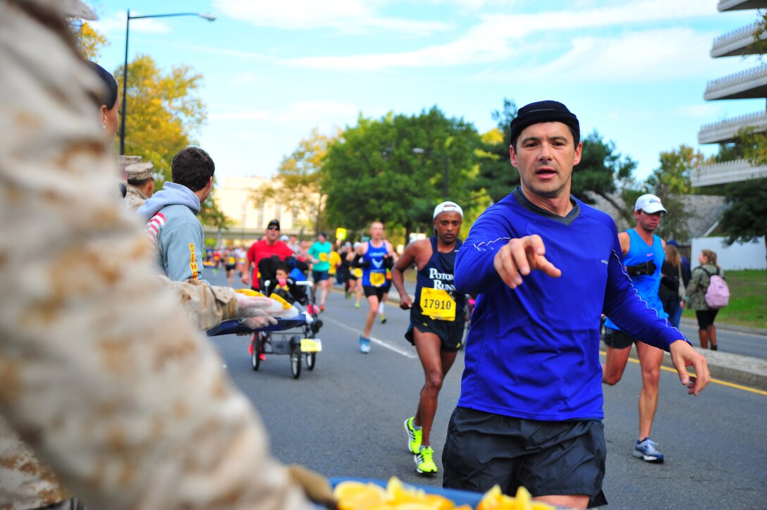 Marathon runners reach out for a slice of orange to recharge their energy at the first food station of the Marine Corps Marathon on Oct. 27, 2013.  The runners had just completed the first nine miles of the race. 