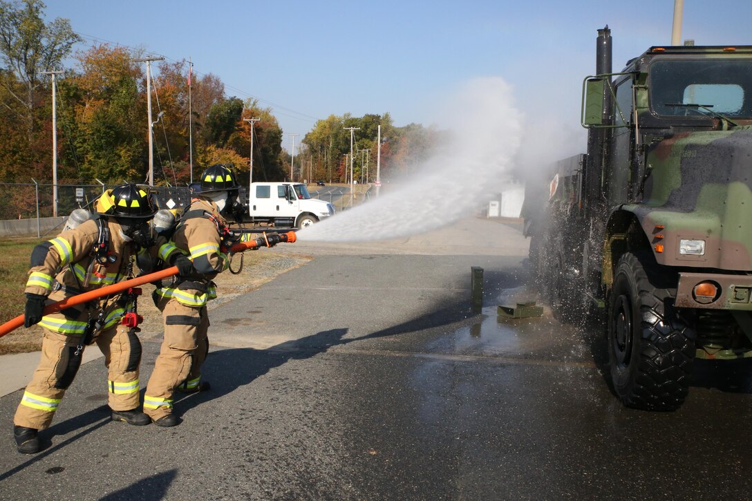 Firefighters Michael Pifer and Marius Cobbs spray a vehicle at the Ammo Supply Point aboard Marine Corps Base Quantico on Oct. 29, 2013. The supply point worked with the Quantico Fire Department to conduct a fire drill.