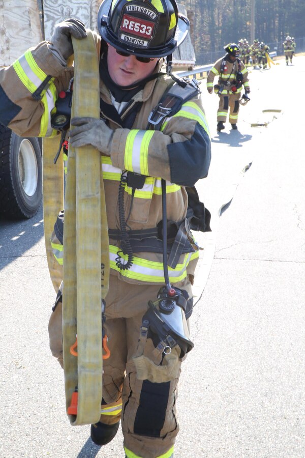Firefighter Michael Pifer drags a hose toward a vehicle at the Ammo Supply Point aboard Marine Corps Base Quantico on Oct. 29, 2013. The supply point worked with the Quantico Fire Department to conduct a fire drill.
