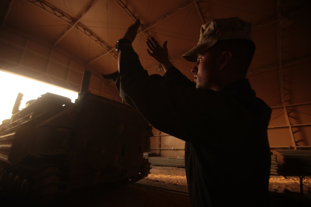 Lance Cpl. Adam M. Blasquez, an Amphibious Assault Vehicle Driver with AAV Platoon, Bravo Company, Battalion Landing Team 1/4, 13th Marine Expeditionary Unit (MEU), from Issaquah, Wash., guides an AAV-P7 into a maintenance bay at Camp Buehring, Kuwait. The 13th MEU is deployed with the Boxer Amphibious Ready Group as a theater reserve and crisis response force throughout the U.S. 5th Fleet area of responsibility. (U.S. Marine Corps photo by Sgt. Christopher O'Quin/Released)