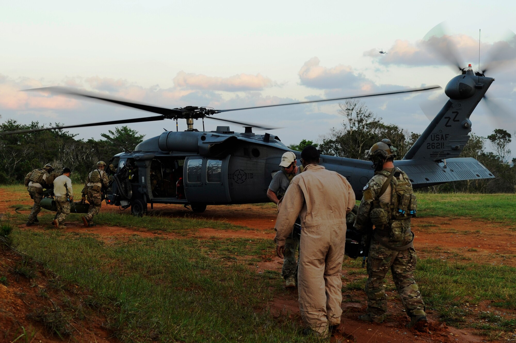 U.S. Air Force Airmen from the 31st Rescue Squadron load simulated casualties onto a HH-60 Pave Hawk helicopter from the 33rd Rescue Squadron during a war week exercise at Marine Corps Camp Hansen's training area, Japan, Oct. 29, 2013. Several volunteers from around Kadena Air Base played roles ranging from opposing forces to injured personnel in order to assist members of the 31st RQS and 33rd RQS in training scenarios. (U.S. Air Force photo by Senior Airman Marcus Morris)   