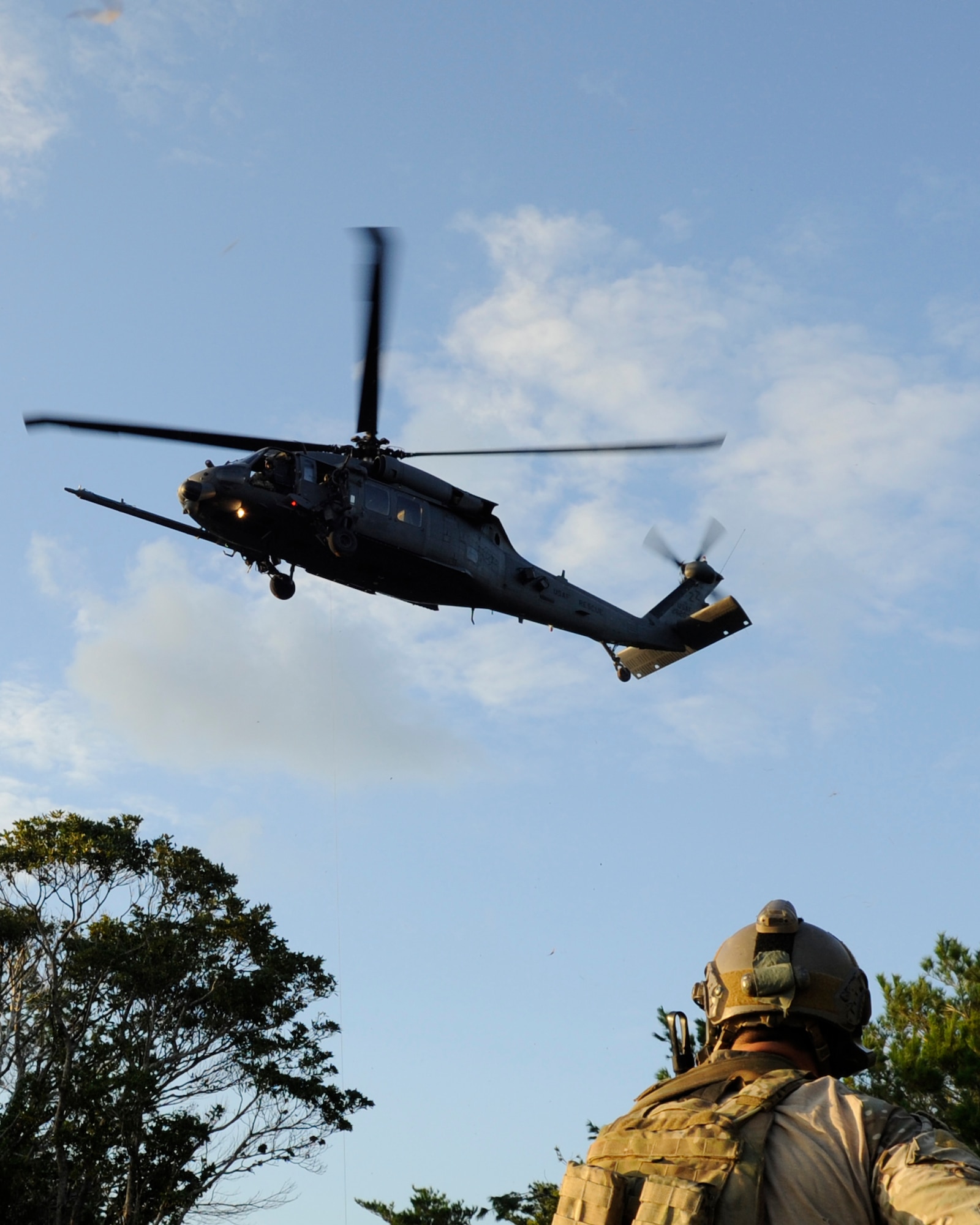 A 31st Rescue Squadron Airman waits for a HH-60 Pave Hawk helicopter from the 33rd Rescue Squadron to descend during a war week exercise at Marine Corps Camp Hansen's training area, Japan, Oct. 29, 2013. The multidimensional exercise allowed the pararescuemen to train for worst-case scenarios to prepare for real-life situations they could experience while deployed. (U.S. Air Force photo by Senior Airman Marcus Morris) 