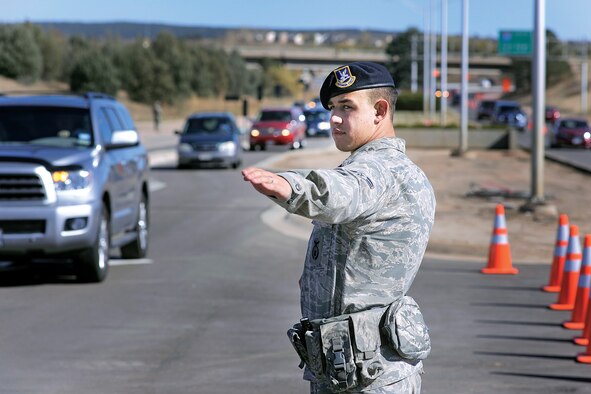A 10th Security Forces Squadron Airman directs traffic through the Academy's north gate to Falcon Stadium for the Air Force vs. Notre Dame football game Oct. 26, 2013. Providing a safe route of travel to the stadium is just one of the many ways security forces Airmen here serve and protect Falcon fans and the U.S Air Force Academy on game day. 