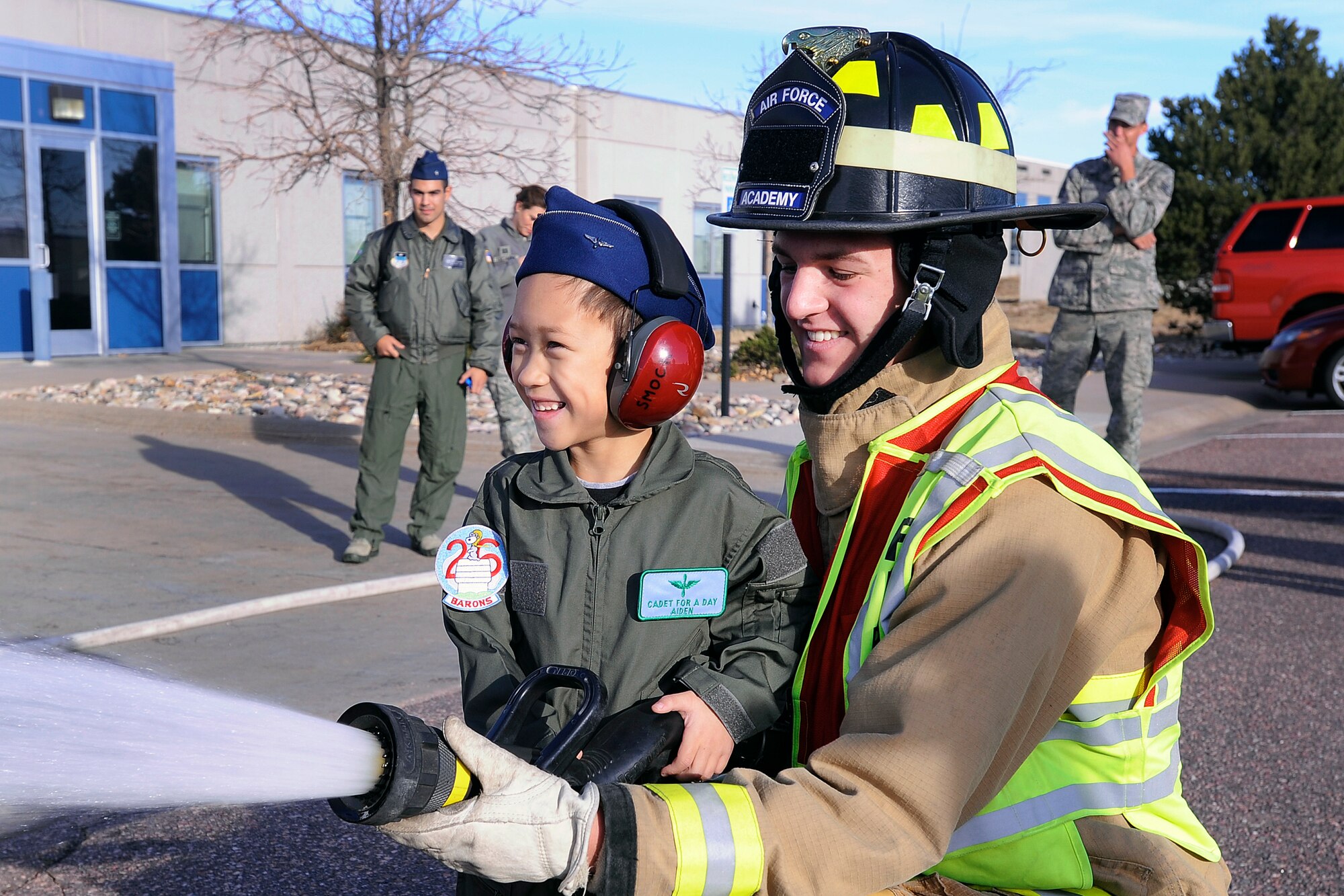 Airman 1st Class Dominic Casa, a 10th Civil Engineer Squadron firefighter, shows Cadet for a Day Aidan Peters how to aim a firehose at the Academy's Fire Station 3  Oct. 25.