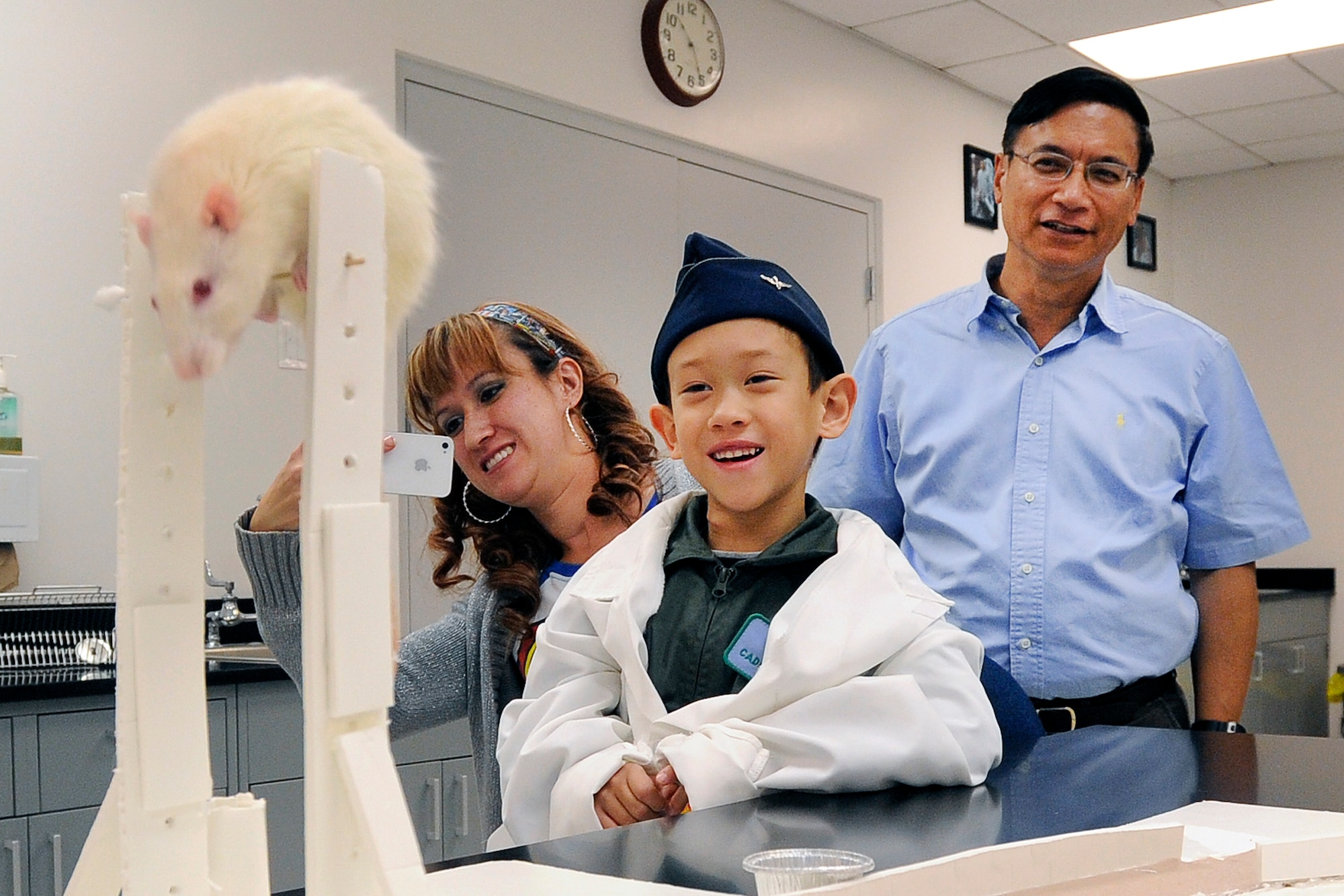 Aidan Peters, the Academy's latest Cadet for a Day, observes a rat in the Behavioral Science and Leadership Department at the Academy Oct. 25 while his mother, April Peters (left) and grandfather, retired Air Force Col. Richard Peters, look on. 