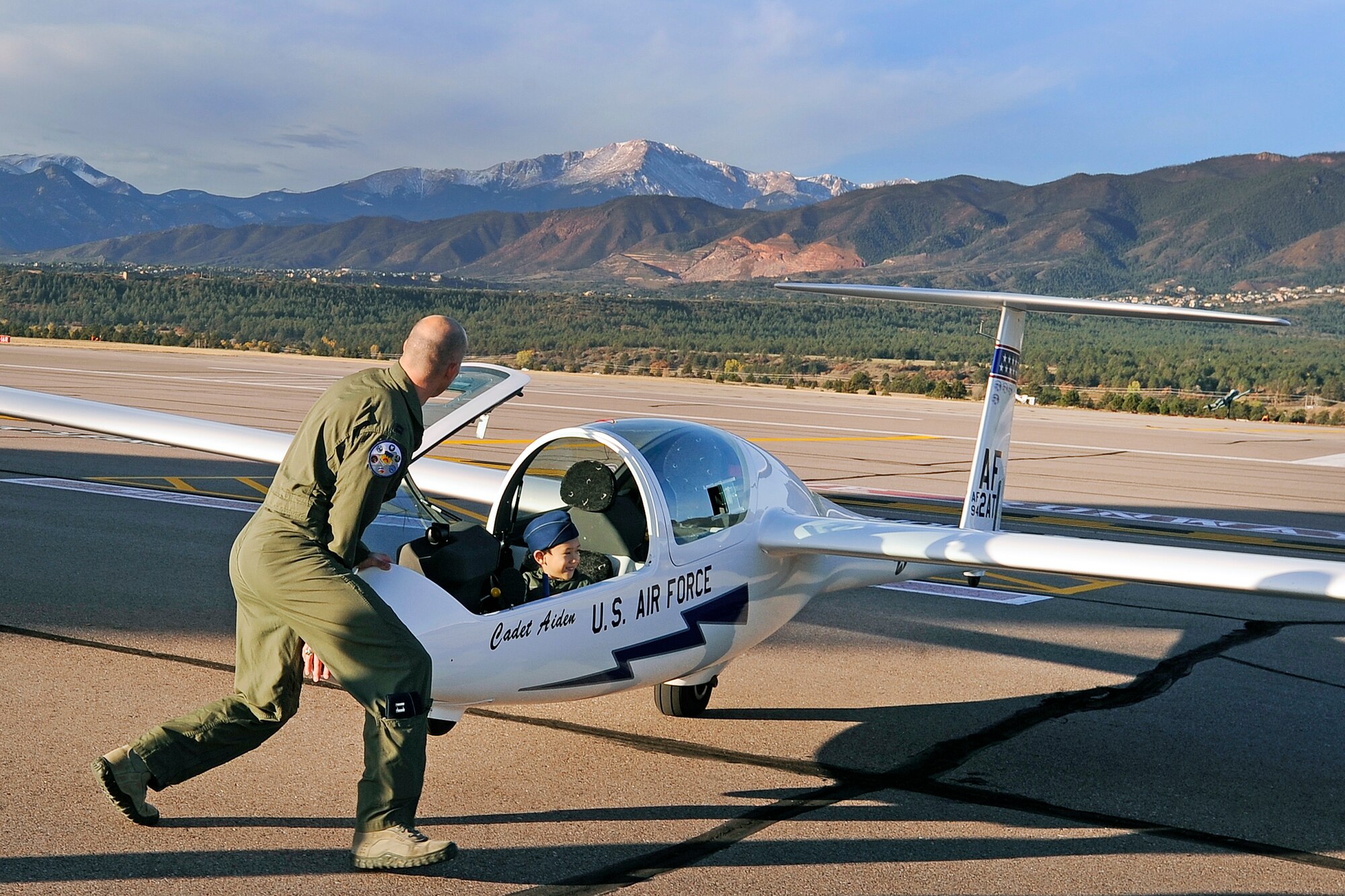 Aidan gets a push from Capt. Joshua McCrary (left) of the 94th Flying Training Squadron while he sits behind the controls of a TG-16A Glider on the Academy Airfield Oct. 25