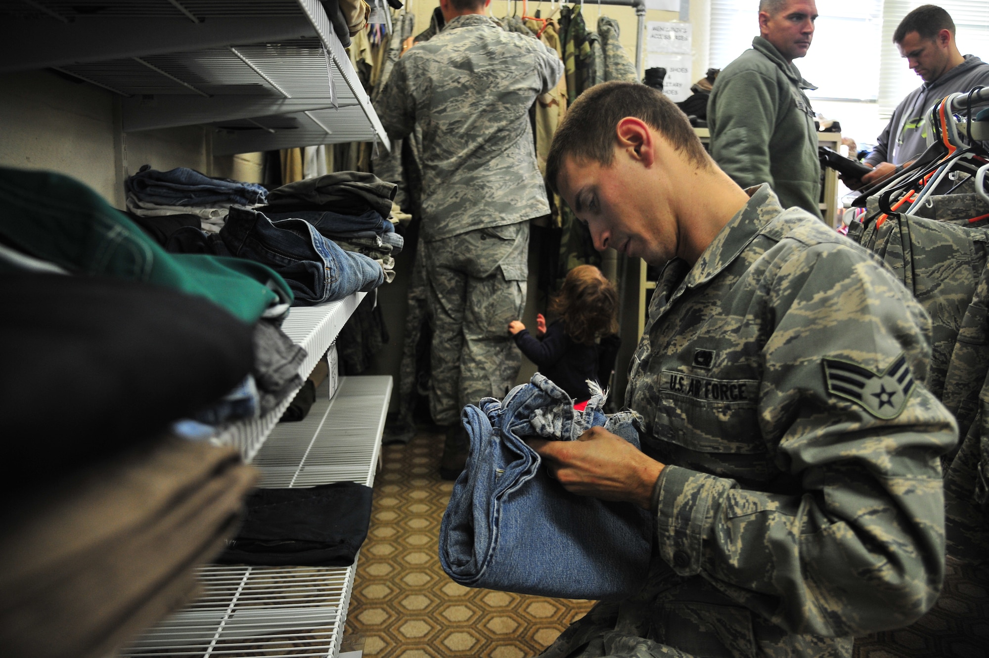 U.S. Air Force Senior Airman Chester Hensley, 4th Aircraft Maintenance Squadron crew chief, checks the size of a pair of jeans in the Airman’s Attic at Seymour Johnson Air Force Base, N.C., Oct. 31, 2013. At the attic, Airmen, E-1 through E-6, and their dependents can acquire items which range from uniforms and children’s toys to electronics, free of charge. (U.S. Air Force photo by Senior Airman Aubrey White)