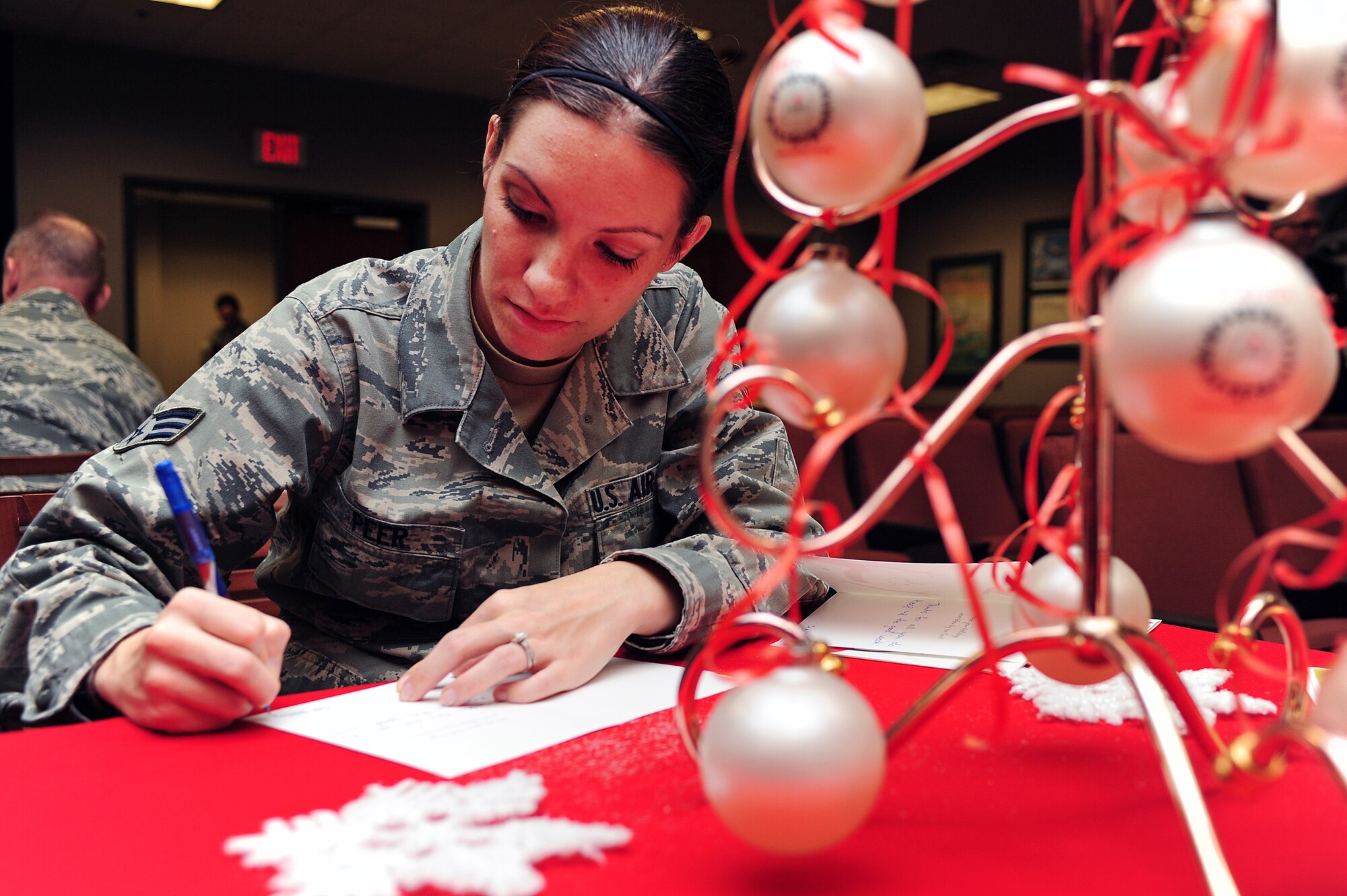 U.S. Air Force Senior Airman Ashley Peer, 911th Air Refueling Squadron knowledge operations manager, signs a card during the American Red Cross Holiday Mail for Heroes event at Seymour Johnson Air Force Base, N.C., Nov. 1, 2013. Team Seymour signed hundreds of cards supplied by the American Red Cross. The cards will be sent to Service members deployed during the holiday season. (U.S. Air Force photo by Airman 1st Class John Nieves Camacho)