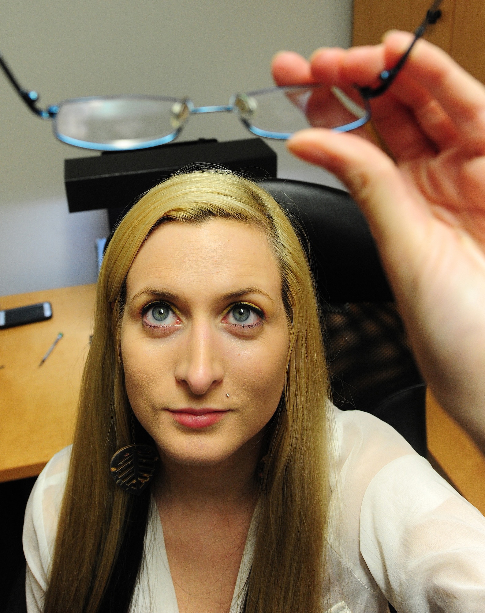 Alyssa White, 509th Medical Operations Squadron optometry technician, checks a pair of eyeglasses for scratches in the optometry clinic at Whiteman Air Force Base, Mo., Sept. 4, 2013. White is checking to see if the glasses are free of irregularities or imperfections in the lenses. (U.S. Air Force photo by Staff Sgt. Nick Wilson/Released)