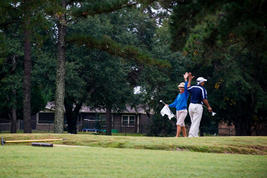 U.S. Air Force Senior Master Sgt. Gerald Richard, 23d Civil Engineer Squadron first sergeant, and Sheila Shaw give each other high-fives after a successful putt during the 2013 Retiree Appreciation Week Golf Tournament at Moody Air Force Base, Ga., Nov. 1, 2013. Sixty-four players signed up for the annual tournament. (U.S. Air Force photo by Staff Sgt. Jamal D. Sutter/Released)