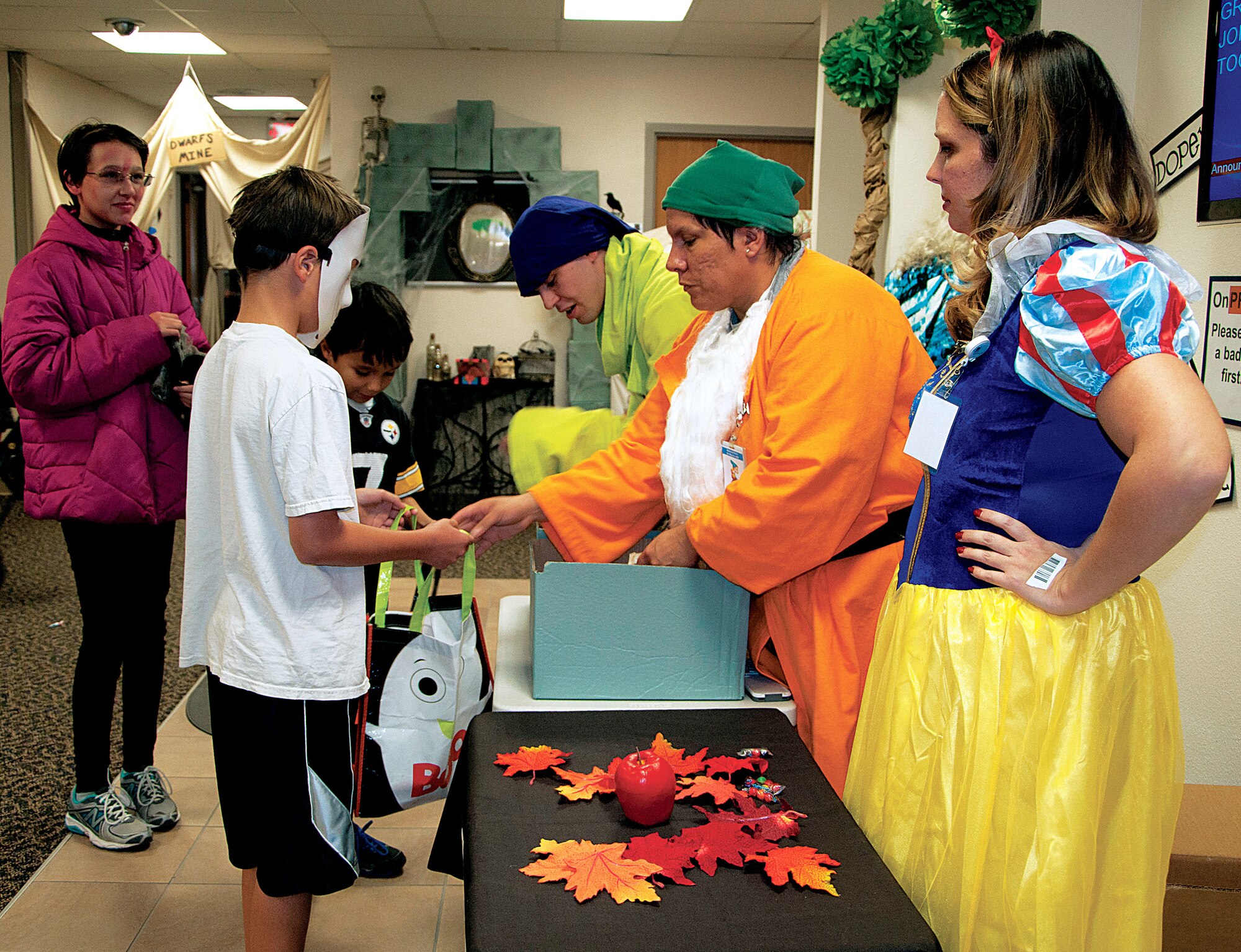 Kaitlyn, 15, Austin, 12, and Mark, 10, children of Master Sgt. Mark Vance, 90th Civil Engineer Squadron, get candy from “Bashful,” Tech. Sgt. Anna O’Neill, 90th Medical Support Squadron, as “Snow White,” Andrea Hull, and “Dopey,” Senior Airman Zachary Nordstrom, 90th MDSS, look on at the 90th Medical Group’s Halloween Event Oct. 31. The 90th MDG hosts a Halloween trick-or-treat event yearly in the clinic. Each section of the clinic had a theme such as the Wizard of Oz, Toy Story, Snow White and the Enchanted Forest, Scooby-Doo, a haunted house and much more. (U.S. Air Force photo by 1st Lt. Eydie Sakura)