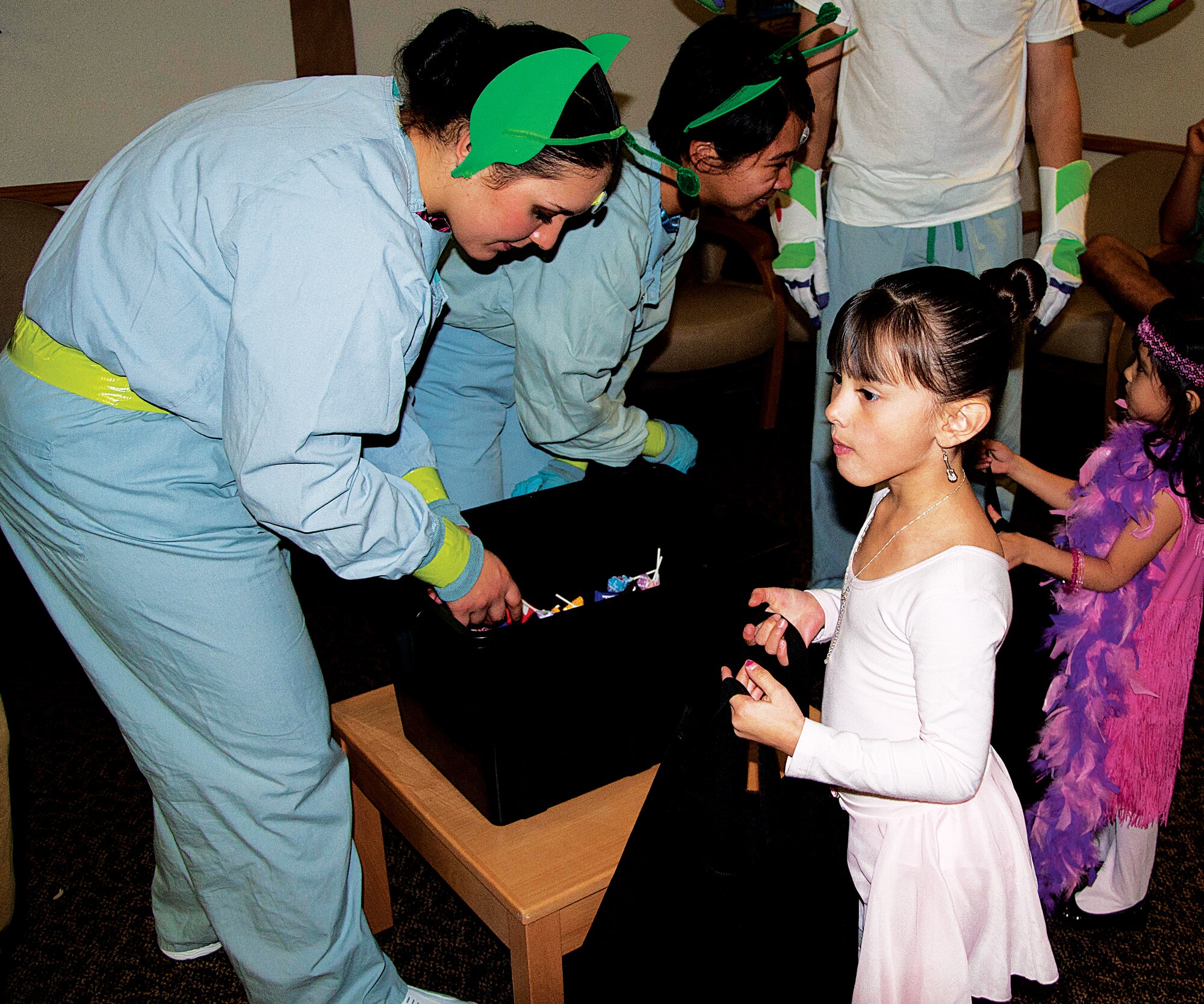 Gracie, 5, and Layla, 4, daughters of Sabrina Pena, 90th Medical Group, get candy from Airman Chelsey Mengel and Airman 1st Class April Tucay, both dressed as some of “Toy Story’s claw machine Martians” assigned to the 90th Medical Operations Squadron, at the 90th MDG’s Halloween Event Oct. 31. The 90th MDG hosts a Halloween trick-or-treat event yearly in the clinic. Each section of the clinic had a theme such as the Wizard of Oz, Toy Story, Snow White and the Enchanted Forest, Scooby-Doo, a haunted house and much more. (U.S. Air Force photo by 1st Lt. Eydie Sakura)