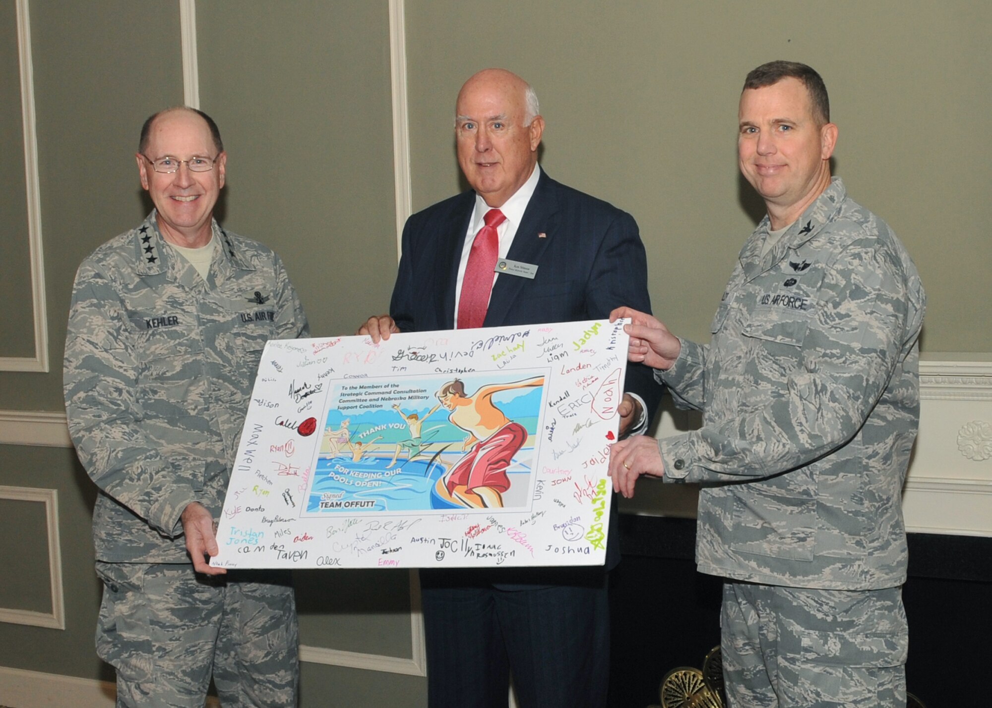 Gen. C. Robert Kehler, commander of U.S. Strategic Command, and Col. Gregory Guillot, 55th Wing commander, present a thank you card to Ken Stinson, Strategic Command Consultation Committee chairman, at the Patriot Club on Oct. 25, at Offutt Air Force Base, Neb. The card was signed by members of the military and their families to express their appreciation to the SCC members for donating nearly $100,000 to the base to reopen the pool this past summer when budget cuts threatened to close it. (U.S. Air Force photo by Steve Cunningham/Released)