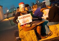 Autumn McGrath, Balfour Beatty Communities LifeWorks coordinator, holds up a sign during a hayride at the Trunk or Treat event, Oct. 31. Balfour Beatty Communities teamed with 5th Logistics Readiness Squadron Vehicle Operations to offer base residents free food and fun at the event. (U.S. Air Force photo/Airman 1st Class Apryl Hall)