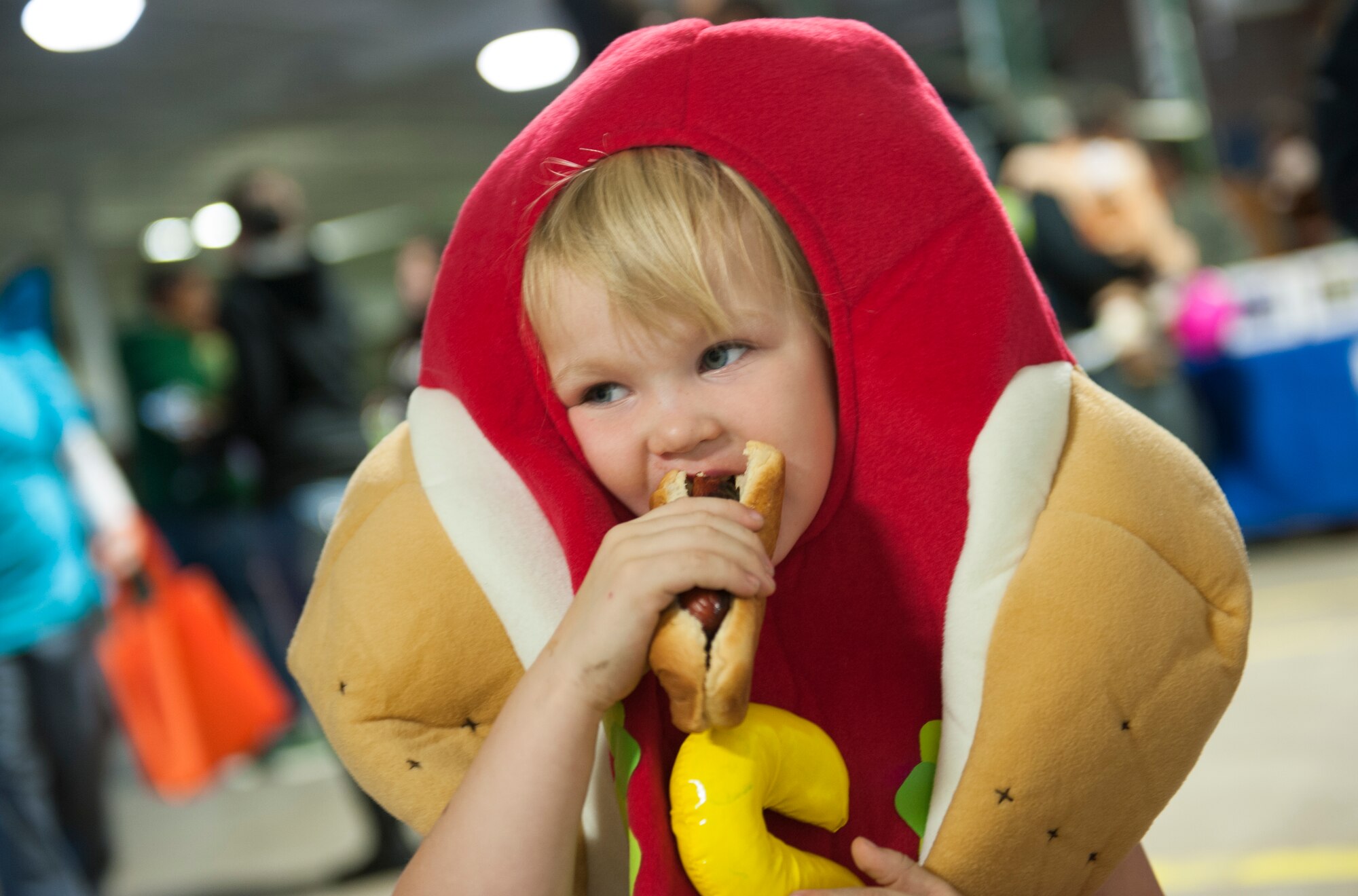 A child dressed as a hotdog takes a bite of a hotdog at the Trunk or Treat event, Oct. 31. The event, hosted by 5th Logistics Readiness Squadron Vehicle Operations and Balfour Beatty Communities, featured treats, an inflatable castle and a haunted house for base residents. (U.S. Air Force photo/Airman 1st Class Apryl Hall)