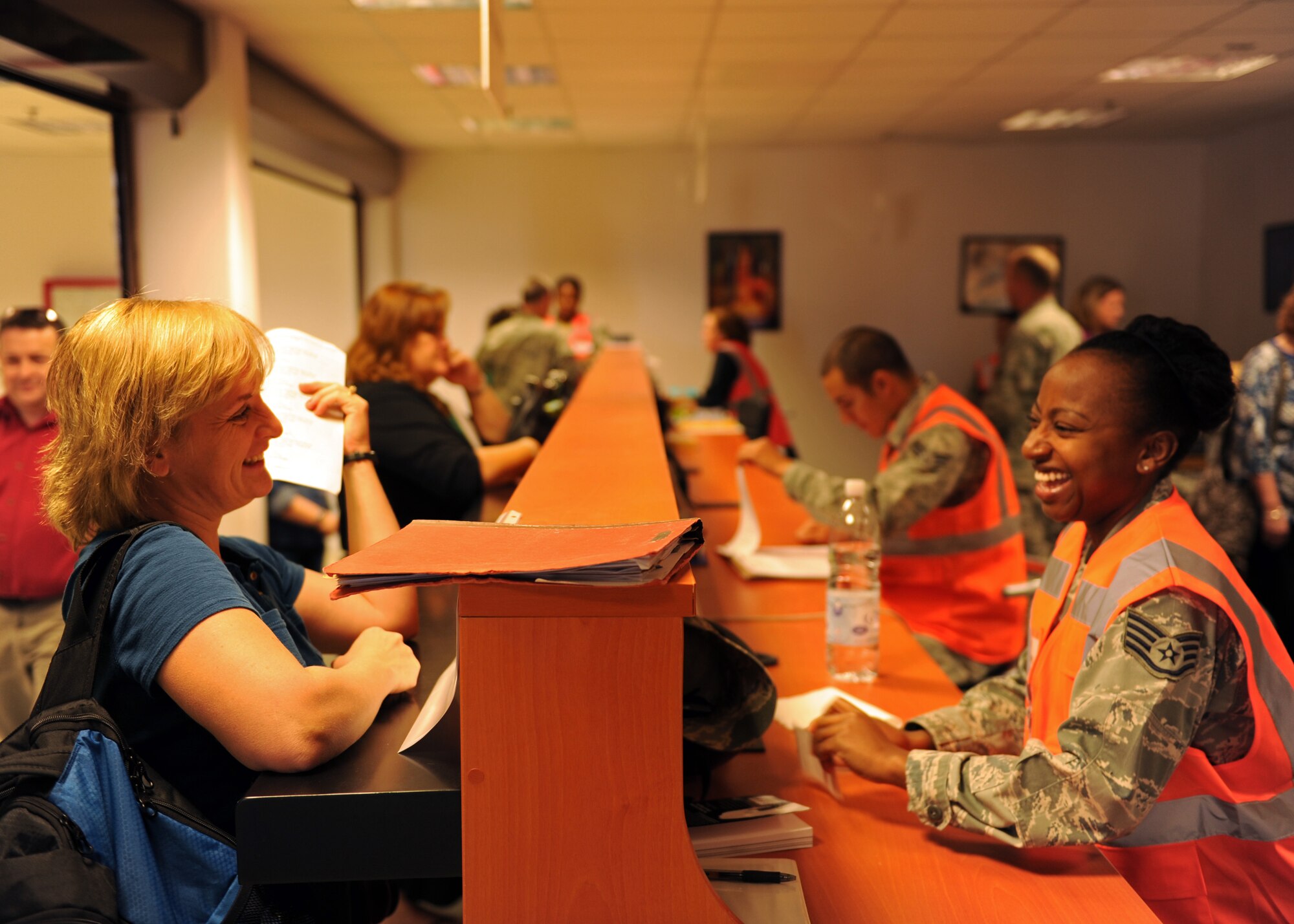 Carla Bigger, 39th Air Base Wing spouse, laughs with Staff Sgt. Adrienne McDonald, 39th Civil Engineer Squadron unaccompanied housing manager, while processing during the noncombatant evacuation operation exercise Oct. 30, 2013, at Incirlik Air Base, Turkey. During the exercise 190 dependents and 13 pets were processed from start to finish. (U.S. Air Force photo by Senior Airman Chase Hedrick/Released)