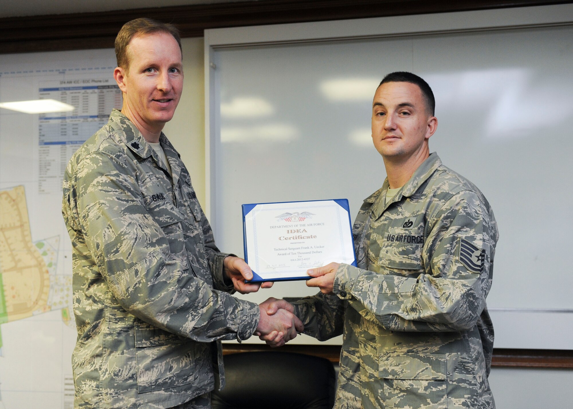 YOKOTA AIR BASE, Japan – Lt. Col. Christoff Gaub, 374th Civil Engineer Squadron commander, left, gives Tech. Sgt. Frank Uecker, 374th CES pavement and construction craftsman an award for his approved idea submitted through the Innovative Development through Employee Awareness program on Oct. 30, 2013, Yokota Air Base, Japan.  Uecker’s IDEA submission will now save the Air Force over $10 million in airfield maintenance costs. (U.S. Air Force photo by Senior Airman Andrea Salazar/Released)