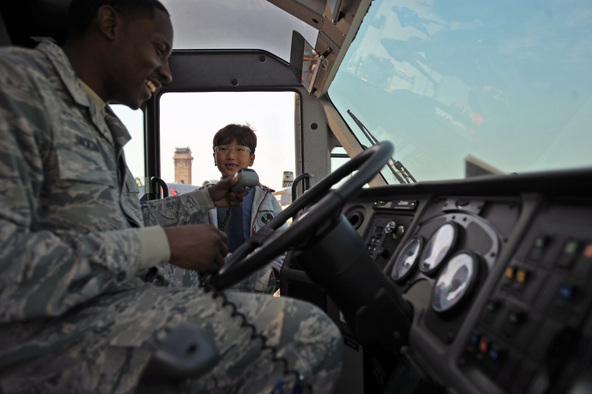 Staff Sgt. Roy Jackson, 51st Civil Engineer Squadron fire crew chief, holds the microphone for a fire truck’s public address system for a U.S. and Republic of Korea Family Day participant at Osan Air Base, ROK, Nov. 1, 2013. Jackson gave active duty members and dependents a tour of the inside of a fire truck and also demonstrated how to use the water hose. (U.S. Air Force photo/Senior Airman Siuta B. Ika)