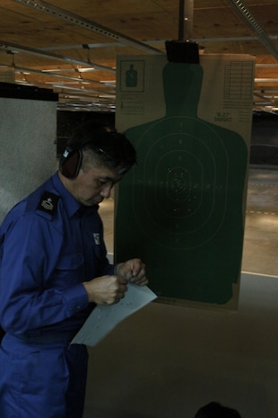 Japanese Maritime Self-Defense Force Petty Officer 1st Class Hiroshi Nagashima, a Fleet Air Wing 31 air crewman, posts a fresh target for the next shooter during rifle re-qualification and familiarization training at the Indoor Small Arms Range here Dec. 2. The sailors shot in groups of six at a time.