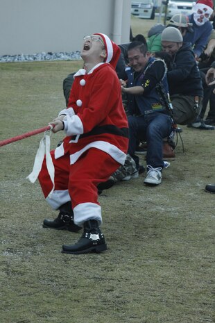 Suehiro Kazuaki, a local motorcyclist who dressed as Santa Claus for the rally, leads the Japanese motorcyclist team during a friendly tug-of-war game with Marines during the 14th annual Toys for Tots Motorcycle Rally at the Strike Zone parking lot here Dec. 4. Nine uniformed Marine volunteers played tug-of-war and wrestled in sumo wrestler suits with some of the Japanese participants.