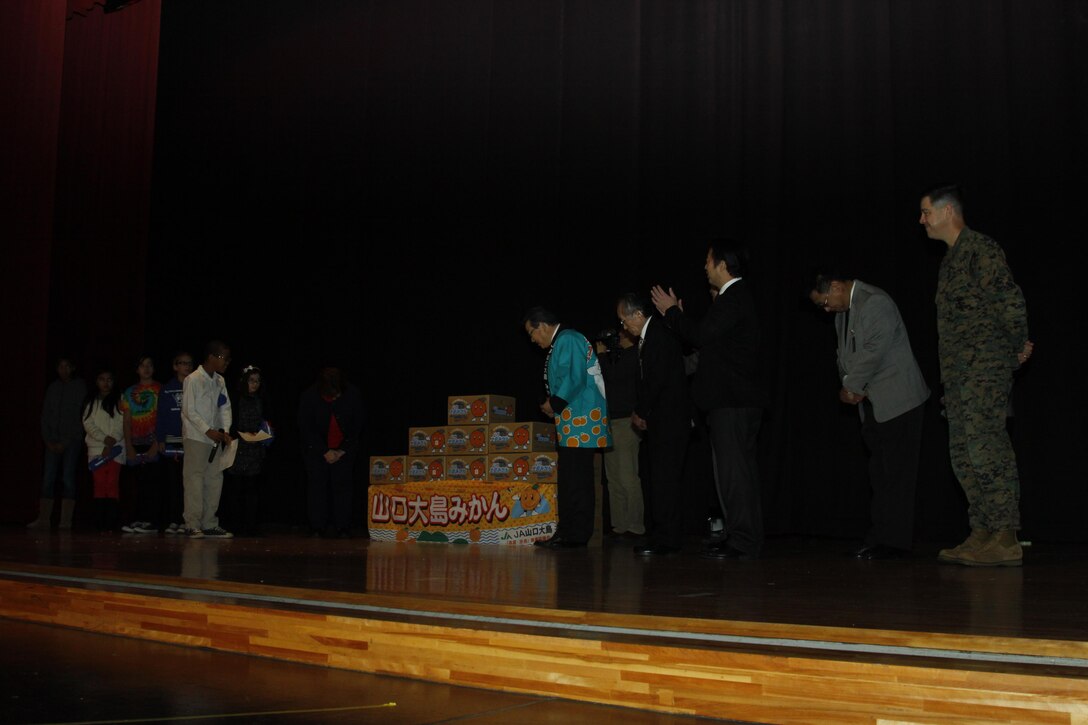 Matthew C. Perry Elementary School student counsel members bow in appreciation to Yoshihiko Fukudo, Iwakuni City mayor, Lt. Col. P.J. Kerr, Marine Corps Air Station Iwakuni executive officer, other distinguished guests and community leaders for the Mikans given during the 2nd annual Mikan Exchange at the Sakura Theater here Dec. 15. The Mikan fruit exchange gave the M.C. Perry children a taste, literally, of Japanese culture.