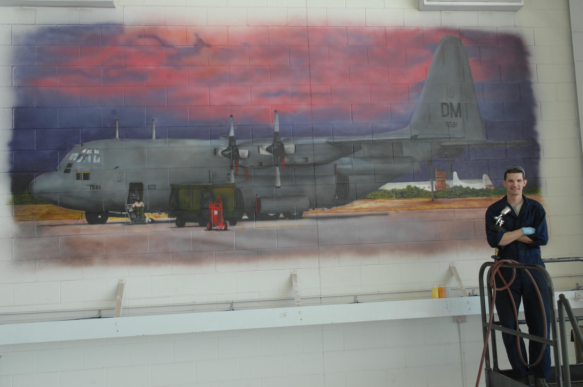 Senior Airman Patrick Corcoran stands in front of a mural he airbrushed Oct. 17, 2013 at Davis-Monthan Air Force Base, Ariz. The mural took him approximately six weeks to complete and is the second of five murals to be painted in the 755th AMXS hanger. Corcoran is a 755th Aircraft Maintenance Squadron propulsion technician.
