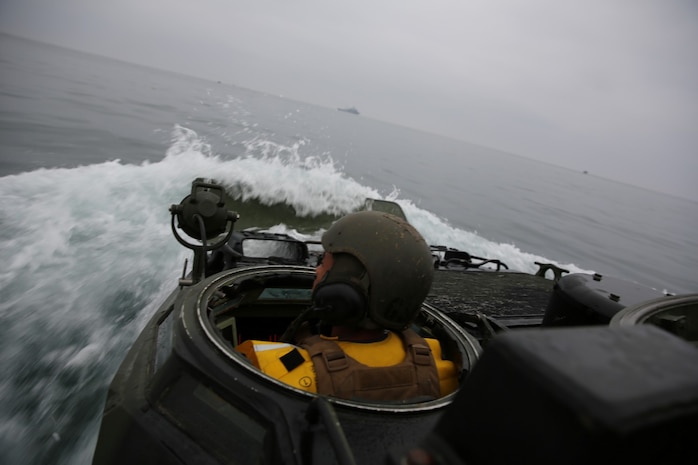 Lance Cpl. Raymond T. Wilcox, amphibious assault vehicle driver, Headquarters and Service Company, 3rd Assault Amphibian Battalion, navigates the AAV during an amphibious landing training exercise in support of well deck operations with the USS Pearl Harbor here, Oct. 24, 2013. The training took place off the coast of Camp Pendleton to train and evaluate the Marines in amphibious operations, wet well procedures and the tactical employment of AAVs in the water and on land.