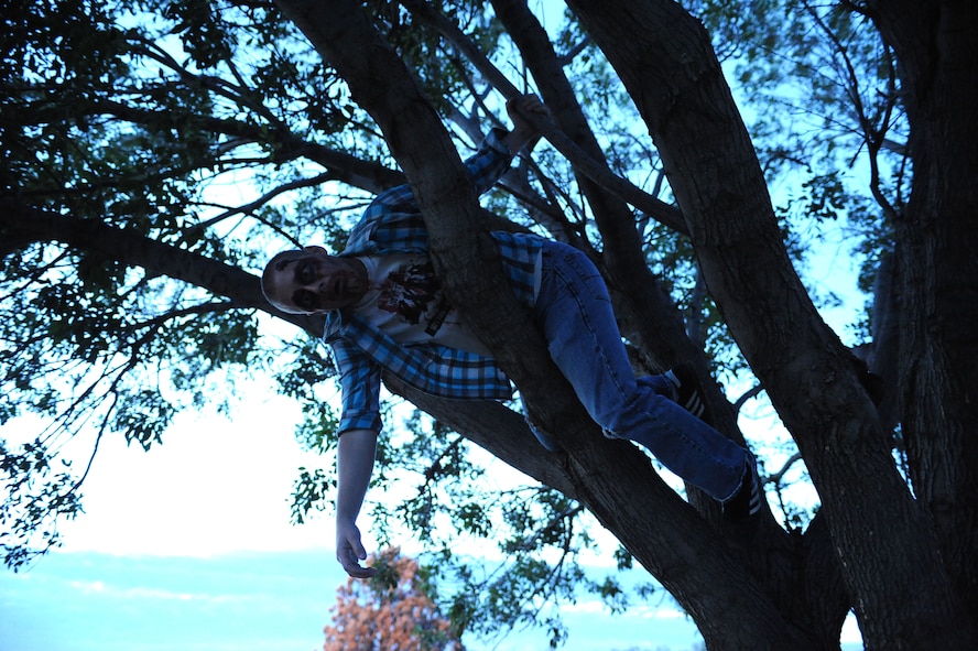 U.S. Air Force Senior Airman Dylan Scamara, 7th Aircraft Maintenance Squadron, hides in a tree Oct. 31, 2013, at Dyess Air Force Base, Texas. Scamara played the role of a zombie during the Post-Apocalyptic Relay, hosted by the Dyess Fitness Center. During this run, Airmen had to make it through a zombie infested area, while collecting items including food, clothing and medicine without being infected. (U.S. Air Force photo by Senior Airman Shannon Hall/Released)