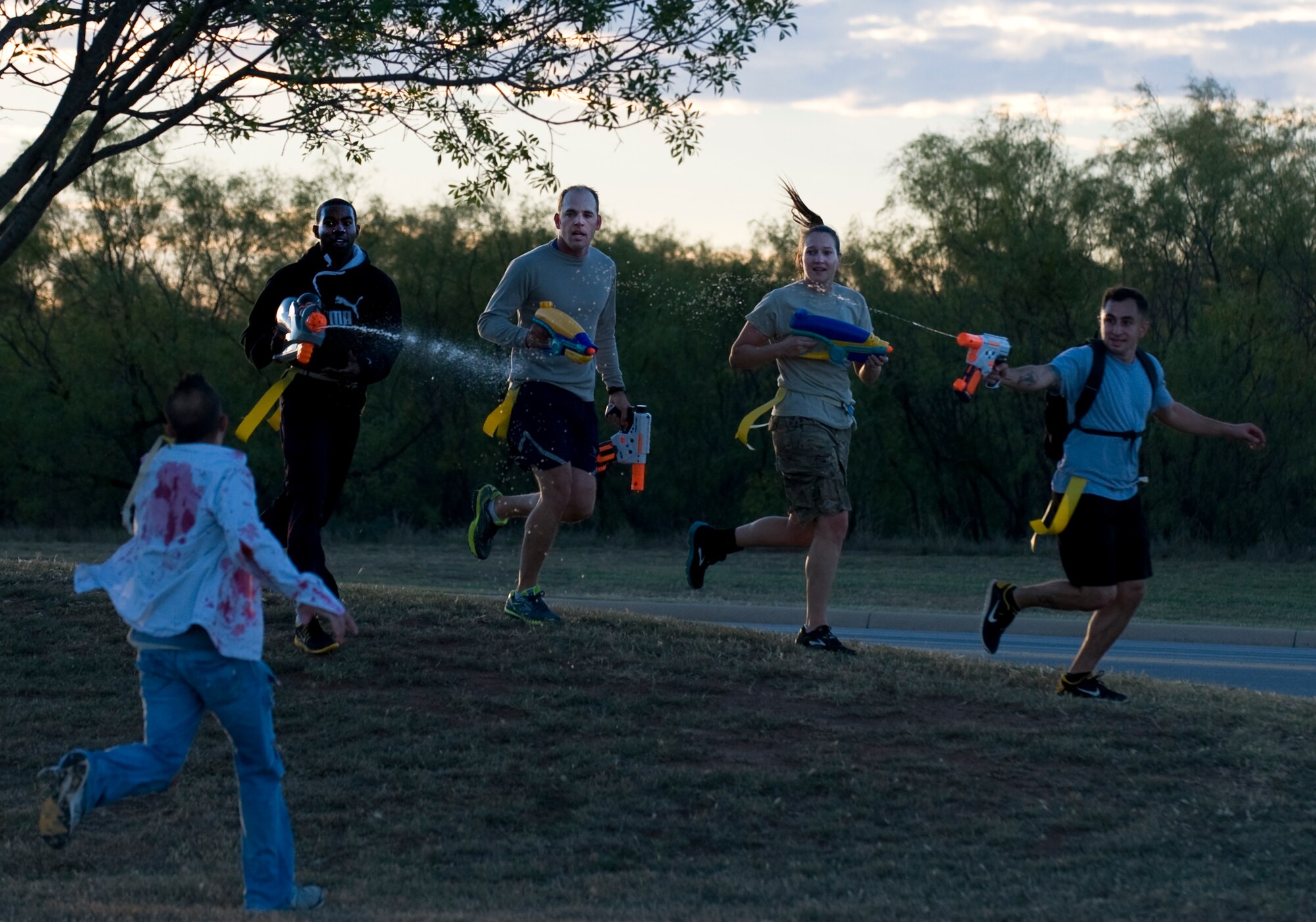A group of Airmen spray Staff Sgt. Jeremiah Hunter, 7th Logistics Readiness Squadron, who was acting as a zombie during the Post-Apocalyptic Relay Oct. 31, 2013, at Dyess Air Force Base, Texas. Participants traveled in teams through the Dyess Air Park avoiding zombies and scavenging for supplies. (U.S. Air Force photo by Senior Airman Peter Thompson/Released) 