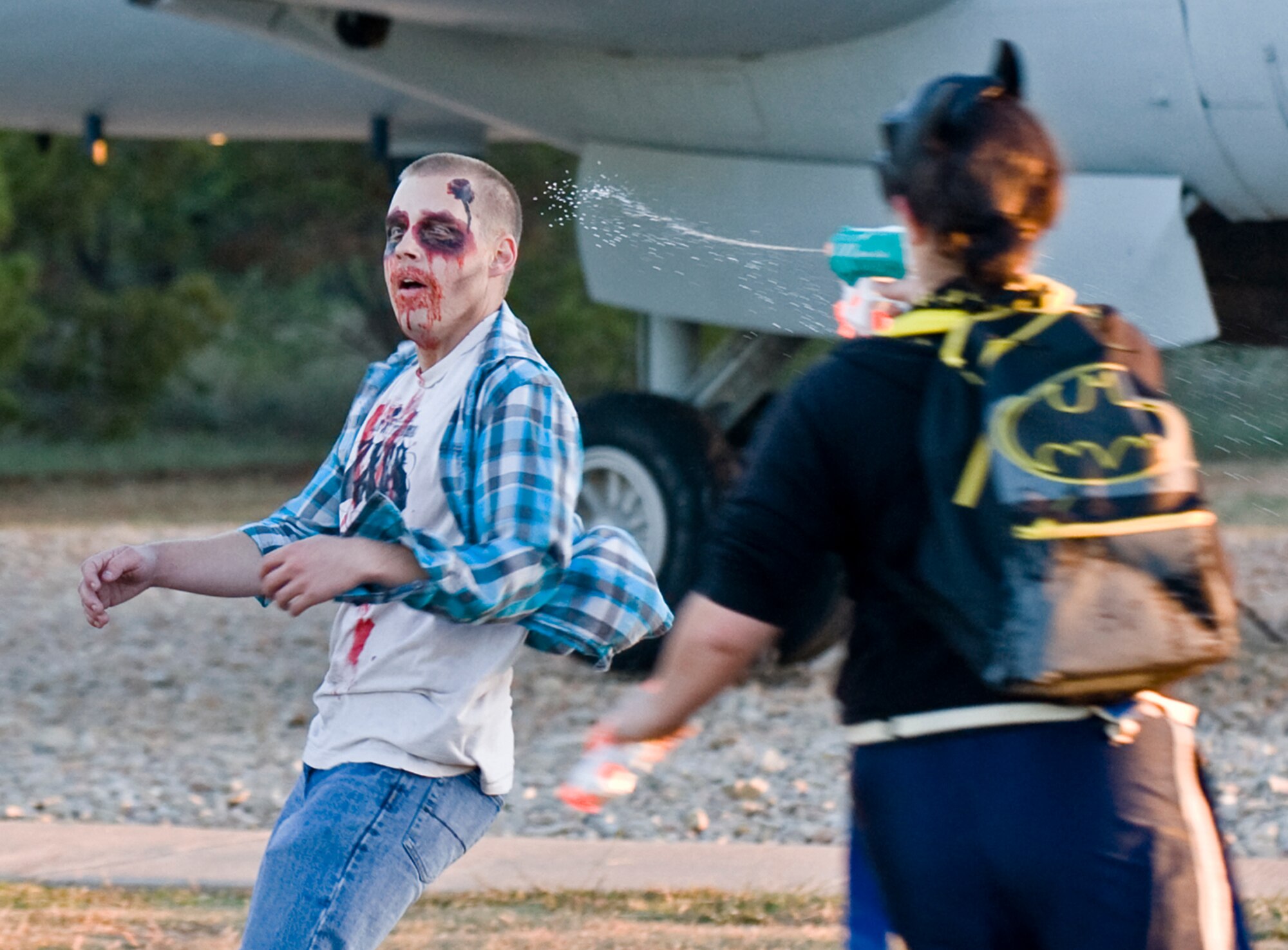 U.S. Air Force Airman 1st Class Brittany Czekalski, 7th Equipment Maintenance Squadron, sprays Senior Airman Dylan Scamara, 7th Aircraft Maintenance Squadron, with a water pistol, during the Post-Apocalyptic Relay Oct. 31, 2013, at Dyess Air Force Base, Texas. Throughout the relay, teams had to collect medicine, food and clothing to help them survive the post-apocalyptic setting. After completing a section, they would turn in supplies, reload with water balloons and head out through the next infection zone. (U.S. Air Force photo by Senior Airman Peter Thompson/Released)