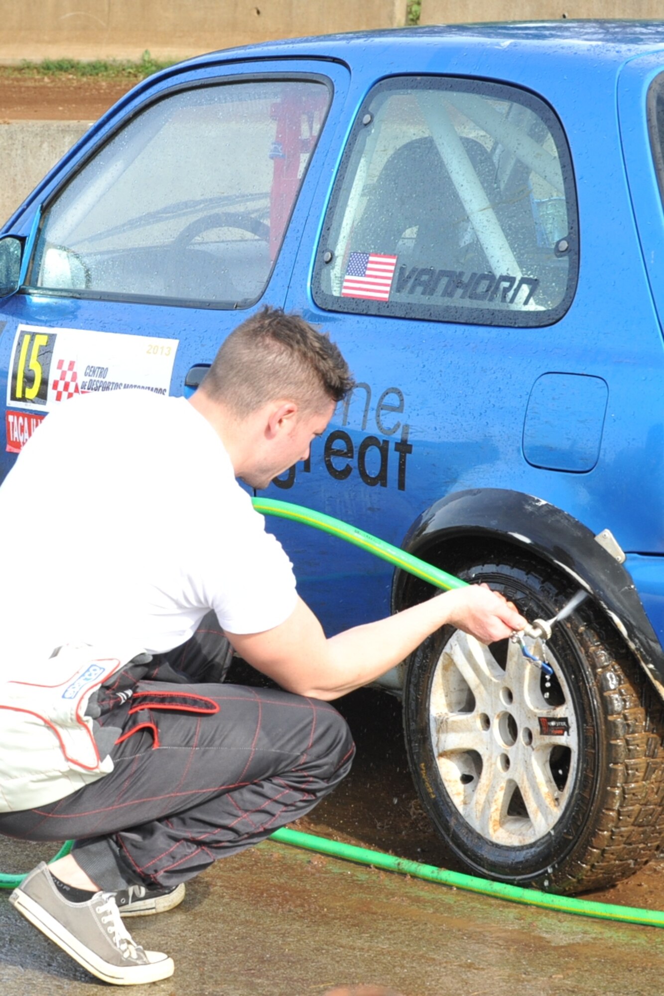U.S. Air Force Staff Sgt. Joshua VanHorn, 65th Medical Operations Squadron medical technician, washes his car after a rally race in Praia da Vitoria, Azores. VanHorn participates in car races with Portuguese local nationals in the Azores while building friendships and host nation relations within the local community. As the only U.S. participant, VanHorn displays an American flag with his last name on his rear driver's-side window. (U.S. Air Force photo by Staff Sgt. Angelique N. Smythe/Released)