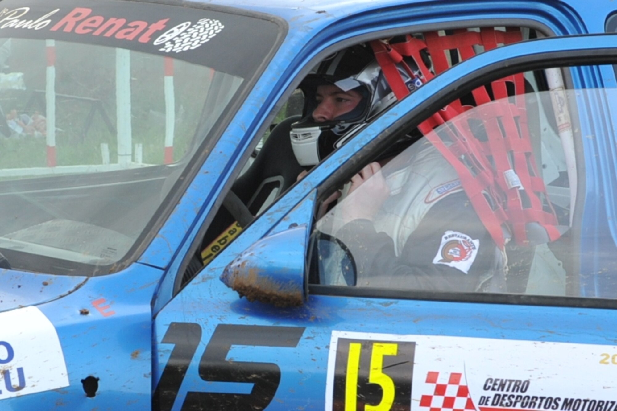 U.S. Air Force Staff Sgt. Joshua VanHorn, 65th Medical Operations Squadron medical technician, dons his helmet before a rally race in Praia da Vitoria, Azores. VanHorn competes in car races with Portuguese local nationals in the Azores while building friendships and host nation relations within the local community. As the only U.S. participant, VanHorn displays an American flag with his last name on his rear driver's-side window. (U.S. Air Force photo by Staff Sgt. Angelique N. Smythe/Released)