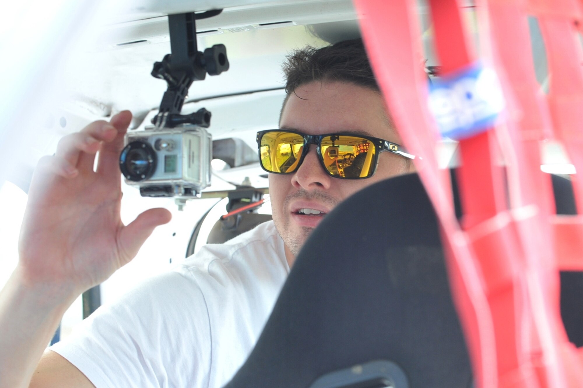 U.S. Air Force Staff Sgt. Joshua VanHorn, 65th Medical Operations Squadron medical technician, installs a GoPro camera inside his race car before a rally race in Praia da Vitoria, Azores. VanHorn competes in car races with Portuguese local nationals in the Azores while building friendships and host nation relations within the local community. As the only U.S. participant, VanHorn displays an American flag with his last name on his rear driver's-side window. (U.S. Air Force photo by Staff Sgt. Angelique N. Smythe/Released)